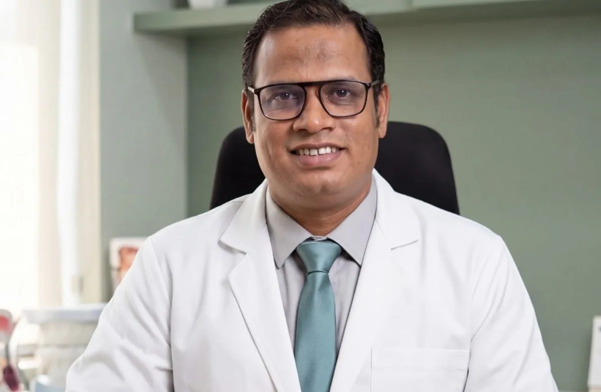 Dr. Ankit Bhagora at his consultation desk at Karnavati Dental Care, with a dental study model and a case folder in front of him