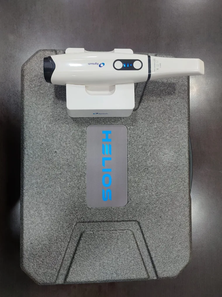 The Eighteeth Helios intraoral scanner wand resting in its charging cradle on top of its grey carry case at Karnavati Dental Care